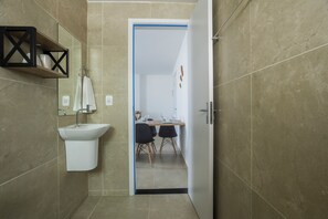 Un baño moderno con un lavamanos blanco, un espejo y una zona de ducha.