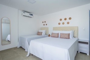 Habitación de hotel con dos camas, una mesita de noche, un espejo y aire acondicionado de pared.