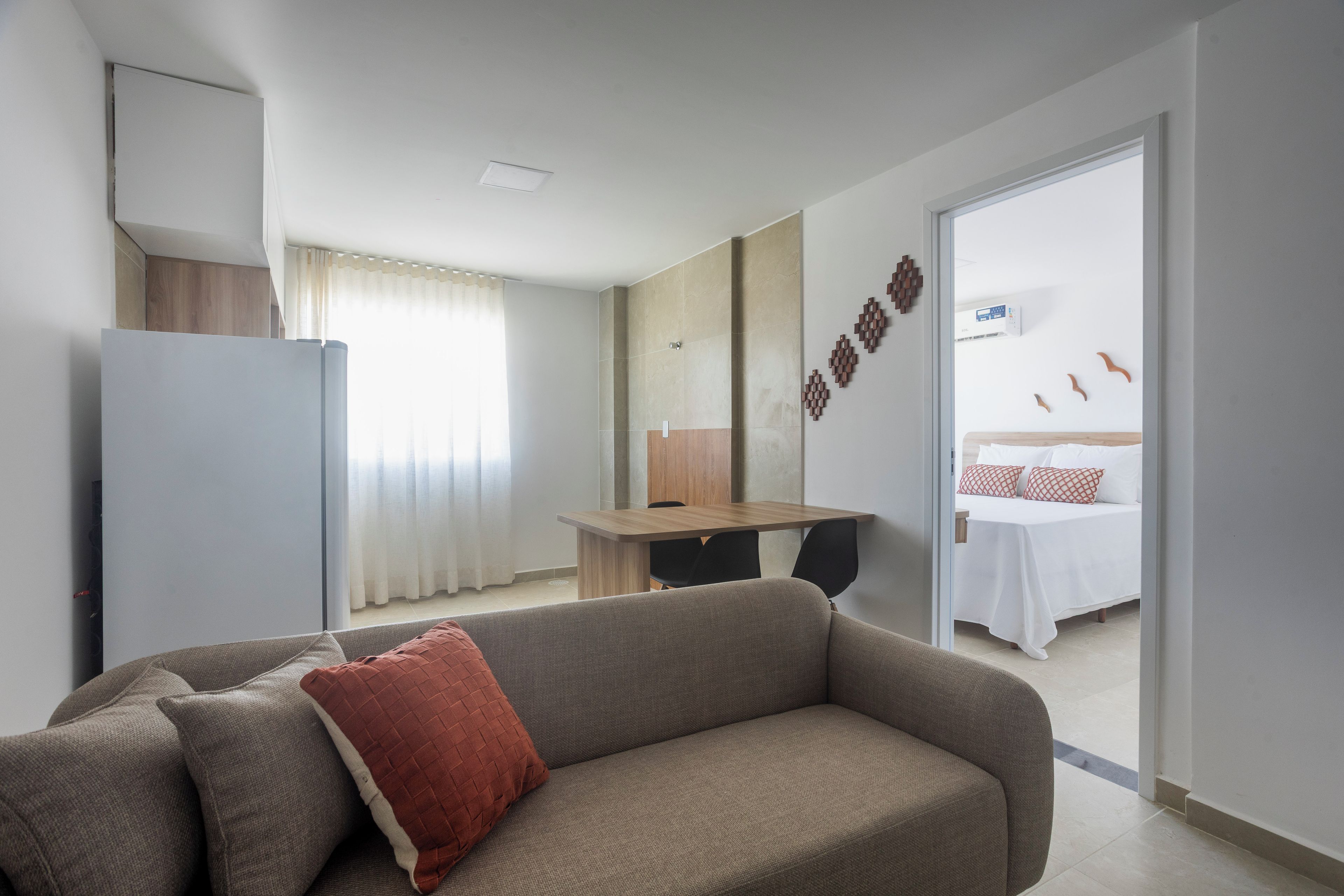 Una habitación de hotel moderna con sofá, cama, zona de comedor y kitchenette.