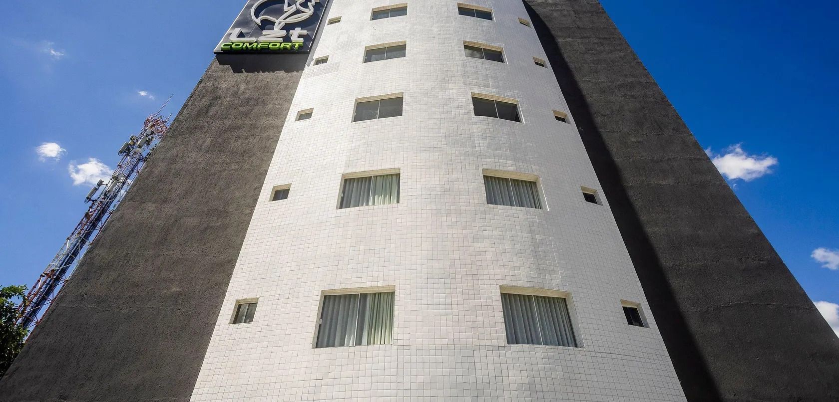Un edificio alto con un reloj en la fachada, múltiples ventanas y un letrero que dice 'COMFORT'.