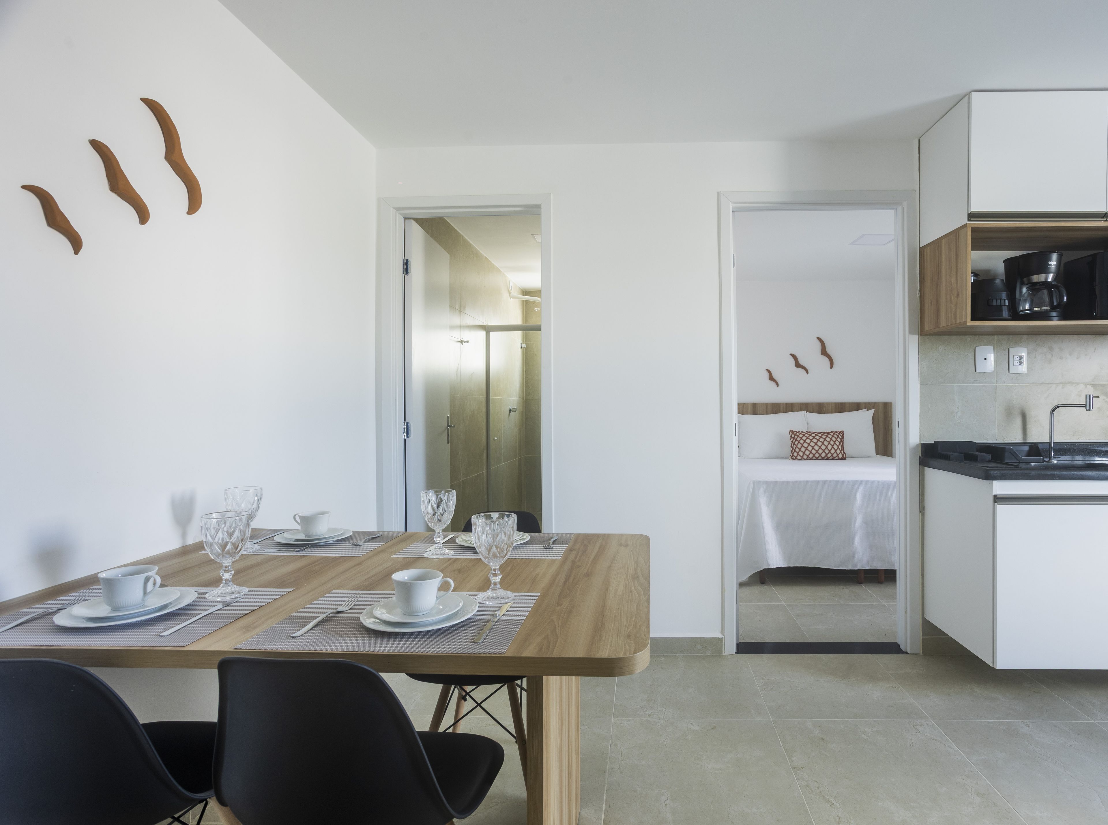Una cocina moderna con armarios blancos, encimera de madera y comedor con una mesa preparada para dos personas.