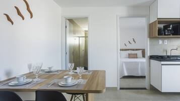 Una cocina moderna con armarios blancos, encimera de madera y comedor con una mesa preparada para dos personas.