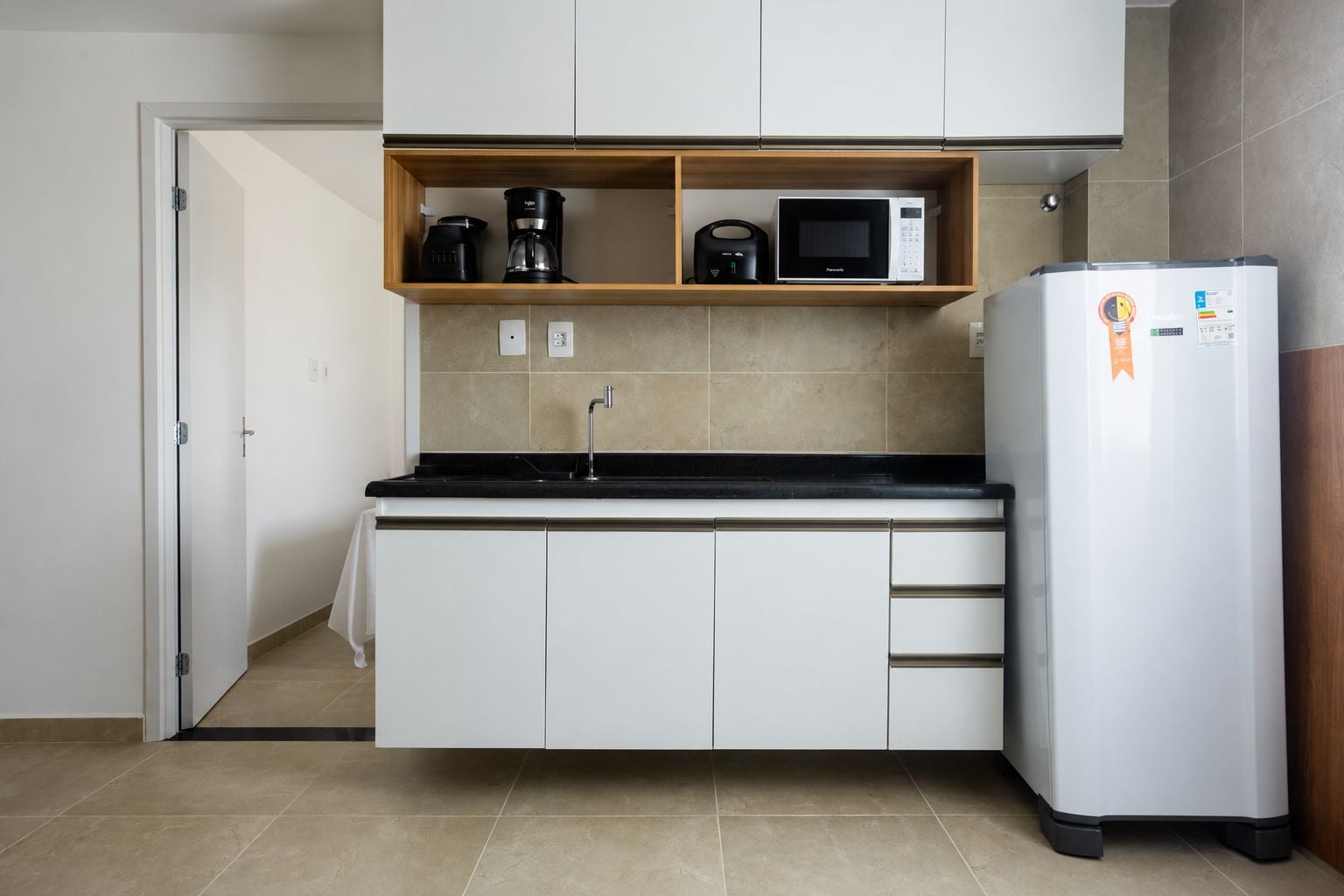 Una cocina compacta equipada con microondas, cafetera y refrigerador.