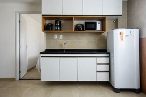 Una cocina compacta equipada con microondas, cafetera y refrigerador.