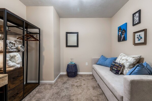A cozy living area with a sofa, a side table, and a bookshelf. - Summit Row | Porch House (Pittsburgh)