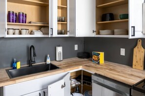 A modern kitchen with built-in cabinets, a sink, and a dishwasher. - Summit Row | Porch House (Pittsburgh)
