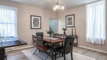 A dining area with a wooden table, black chairs, a chandelier, and framed artwork on the walls.