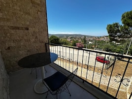 Un balcón con vista a un pueblo, una mesa y dos sillas.