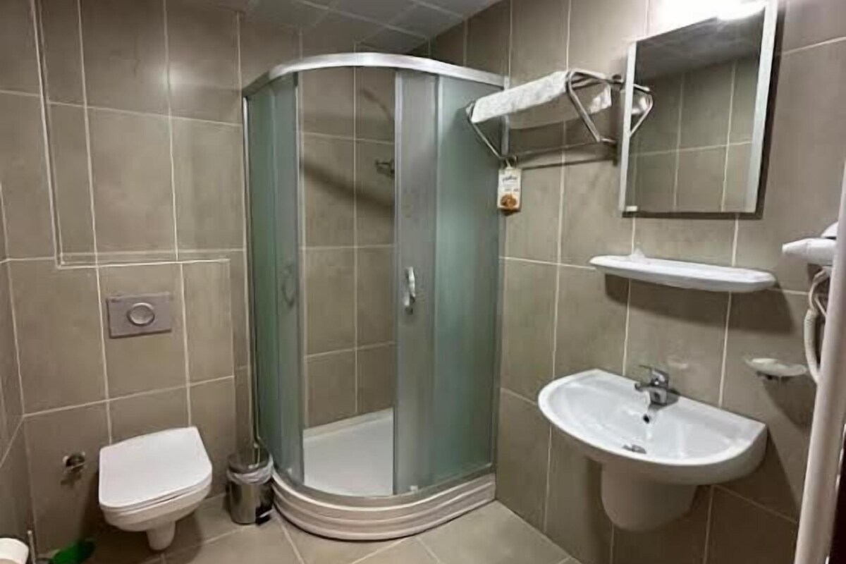 Un baño con ducha de vidrio, lavamanos y retrete.