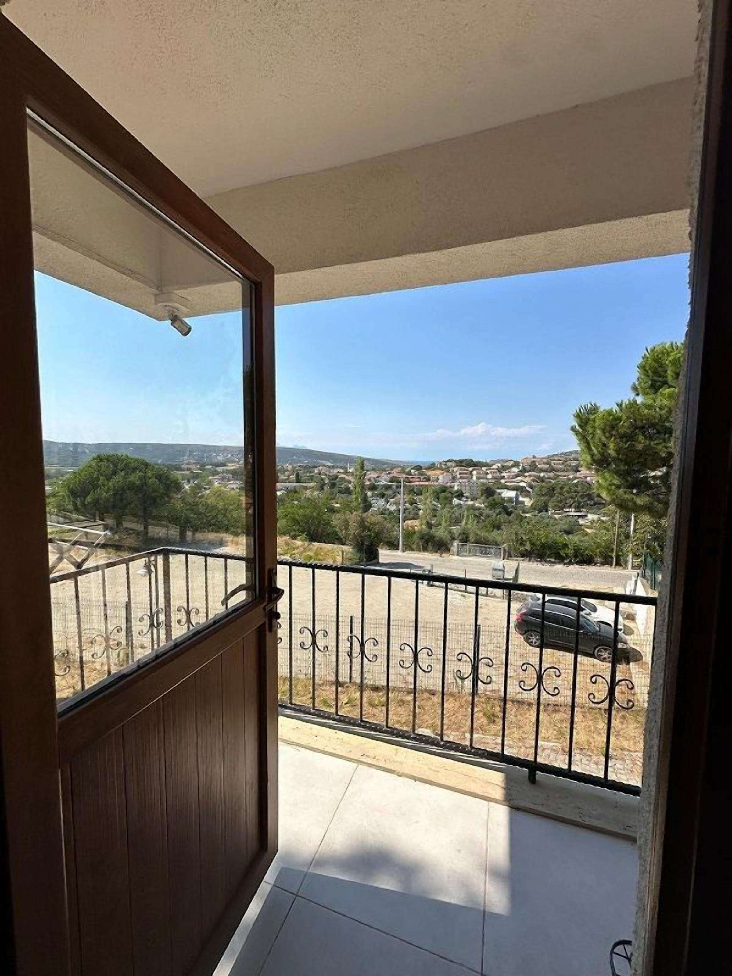 Ein Balkon mit Blick auf eine Stadtlandschaft, einem Metallzaun und einer Tür, die zum Balkon führt.