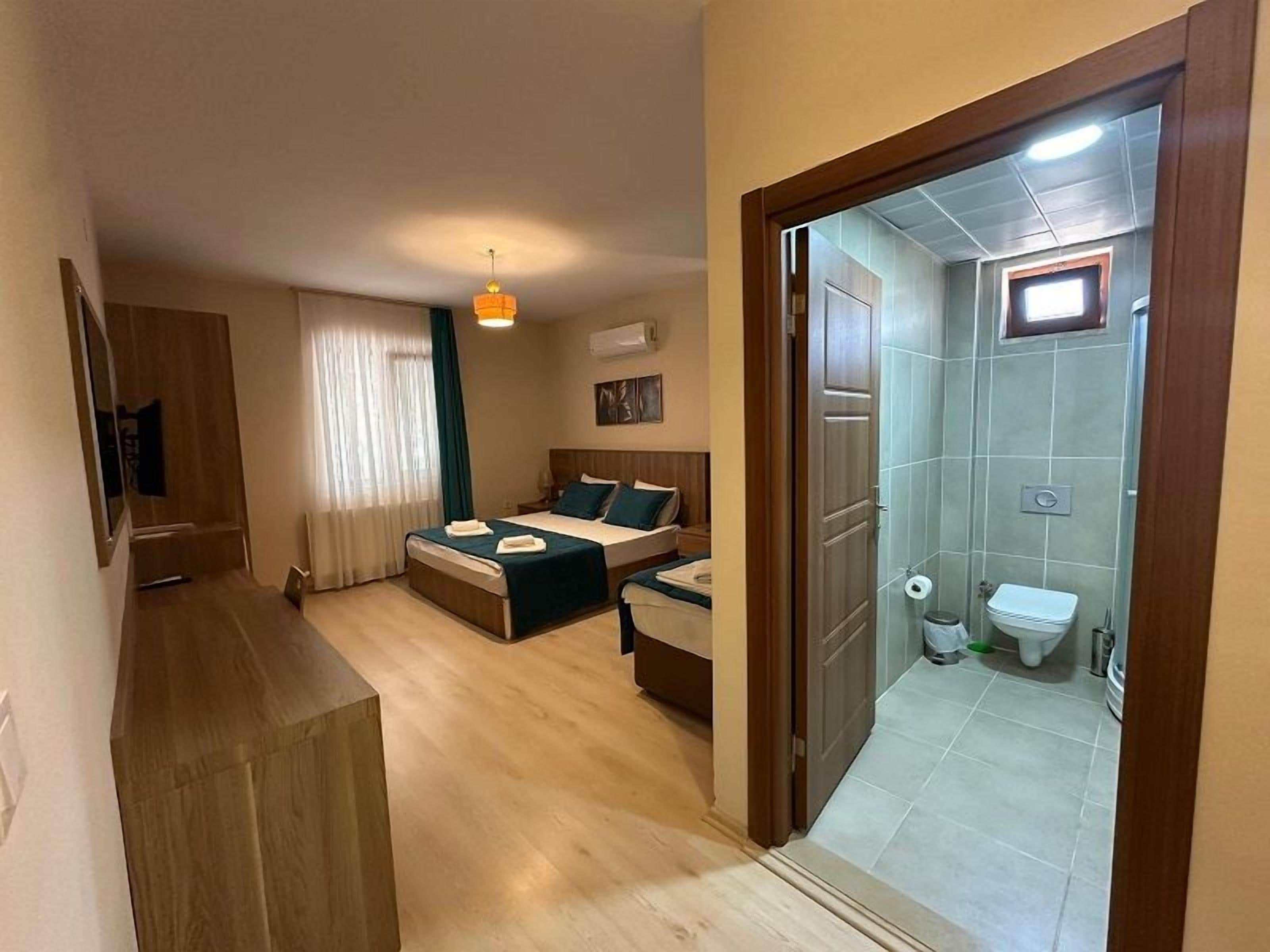 Ein Hotelzimmer mit Bett, Schreibtisch, Stuhl, kleinem Tisch, Spiegel und einem Badezimmer mit Toilette und Waschbecken.