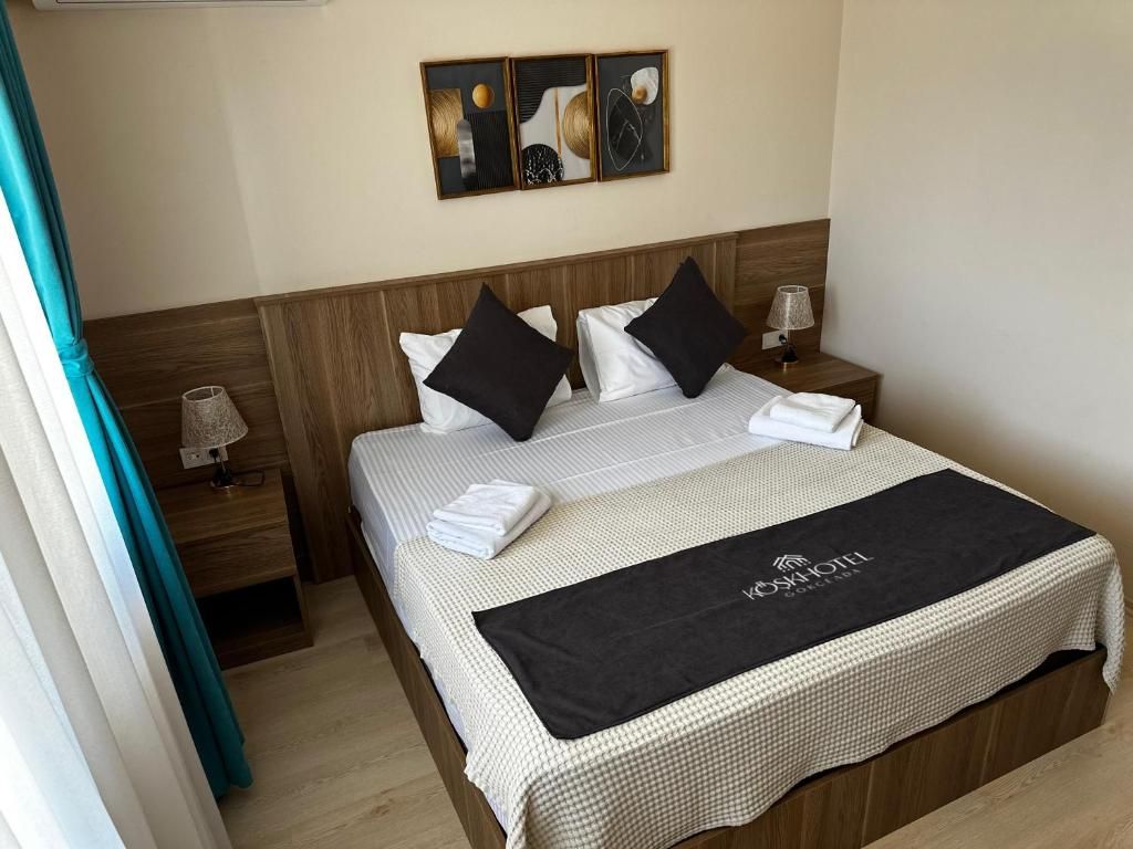 A hotel room with a bed, a nightstand, a lamp, and artwork on the wall.
