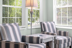 Una habitación con sillones a rayas, una mesita y una lámpara de pie.
