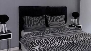 Un dormitorio con una cama, dos mesitas de noche y una colcha con estampado de cebra.