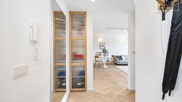 Un interior moderno con suelo de madera, un teléfono blanco montado en la pared y una puerta corredera de cristal que da a un comedor.