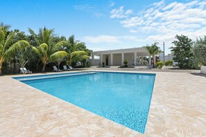 A swimming pool with lounge chairs and palm trees. - 2BR Townhome w/Fast Wi-Fi, Backyard, Gazebo & Pool (Punta Cana)