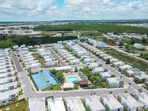 A residential complex with multiple apartment buildings, a central swimming pool, and surrounding greenery. - 2BR Townhome w/Fast Wi-Fi, Backyard, Gazebo & Pool (Punta Cana)
