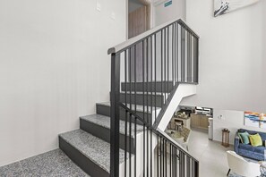 A staircase with black railings leading to a living area with a sofa and a coffee table. - 3BR Villa w/ Patio, Pool Near Downtown & Beaches (Punta Cana)