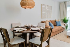 A dining area with a round table, chairs, and a hanging light fixture. - High-end 2BR w/Private Pool + BBQ + Steps to Beach (Punta Cana)