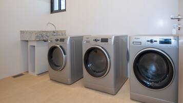 Een wasserette met drie voorlaadwasmachines, een aanrecht en een raam boven de machines.