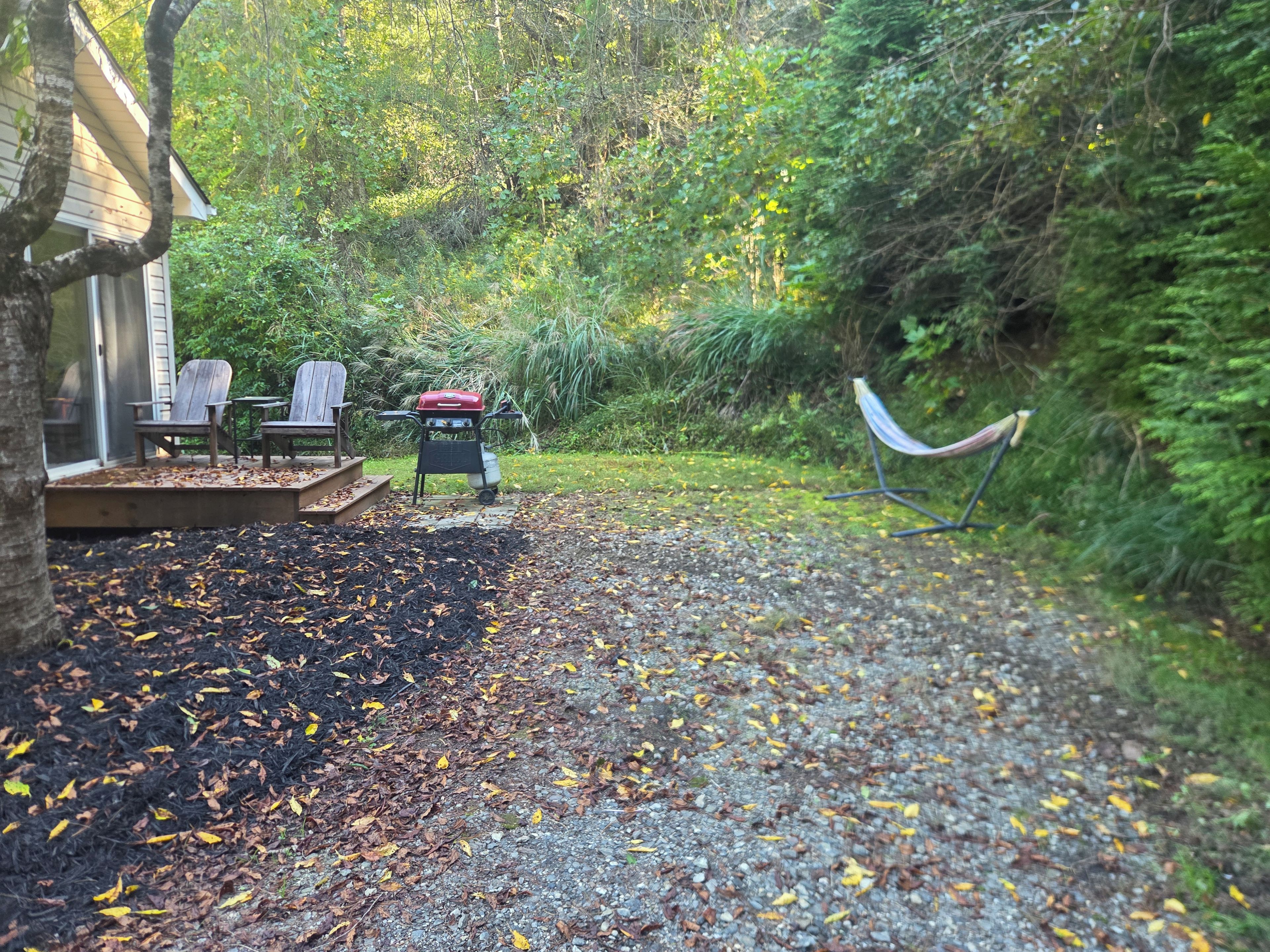 A covered outdoor seating area with chairs and a barbecue grill.