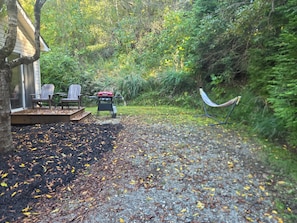A covered outdoor seating area with chairs and a barbecue grill. - Peaceful cottage in a private setting on 12 acres in the country (Weaverville)