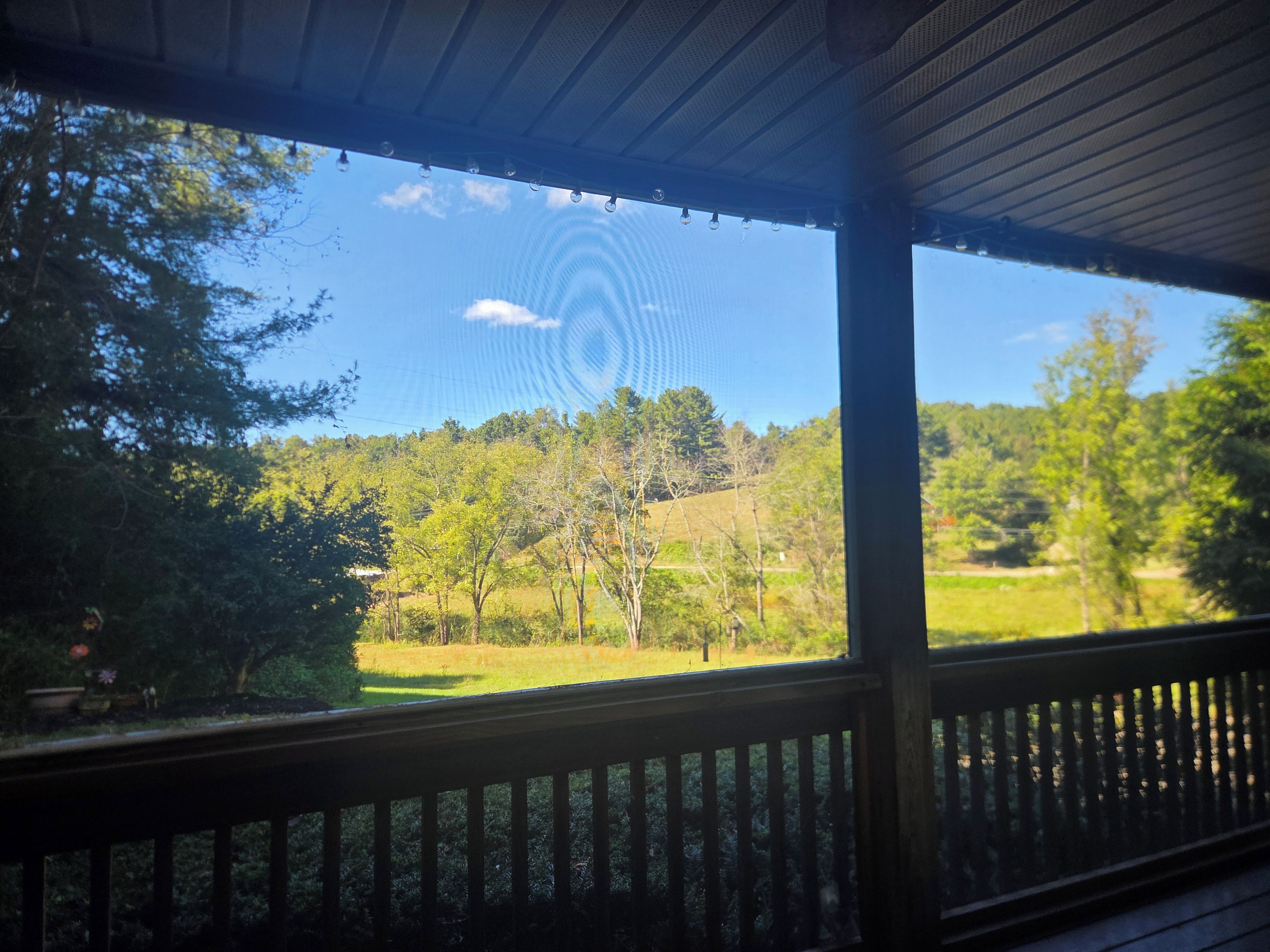 Un espacio al aire libre techado con vistas a un paisaje verde y árboles.
