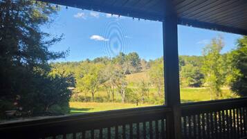 Un espacio al aire libre techado con vistas a un paisaje verde y árboles.