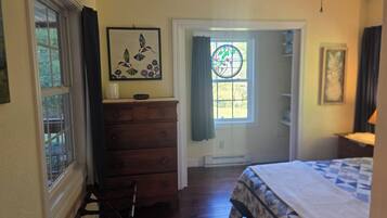 A bedroom with a bed, dresser, chair, and a door leading to a balcony.