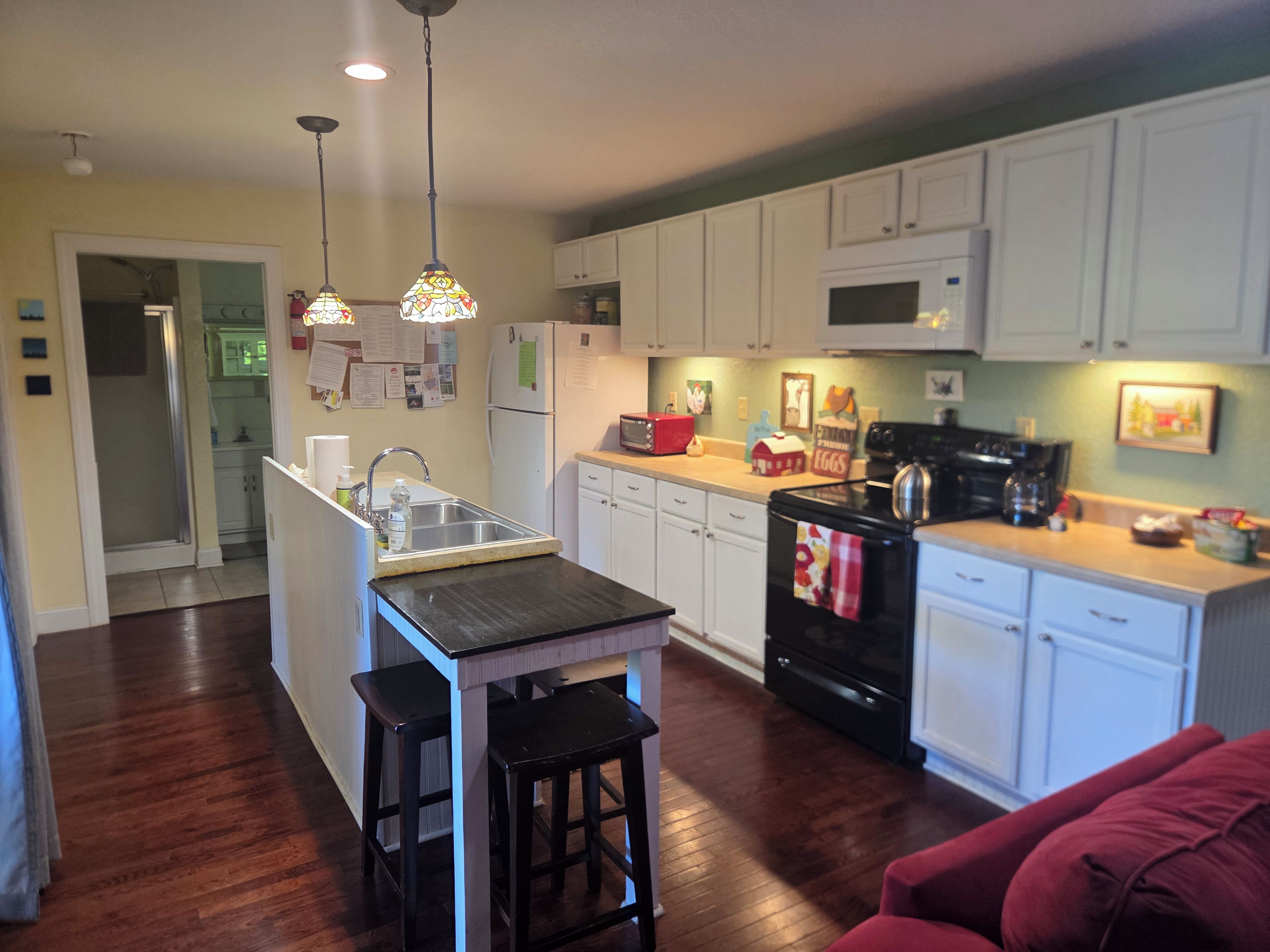 A kitchen with white cabinets, a black stove, and a wooden island with stools.