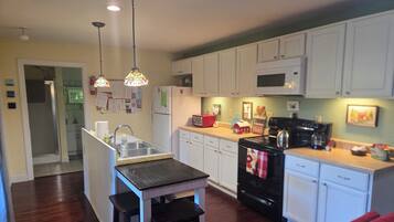 A kitchen with white cabinets, a black stove, and a wooden island with stools.