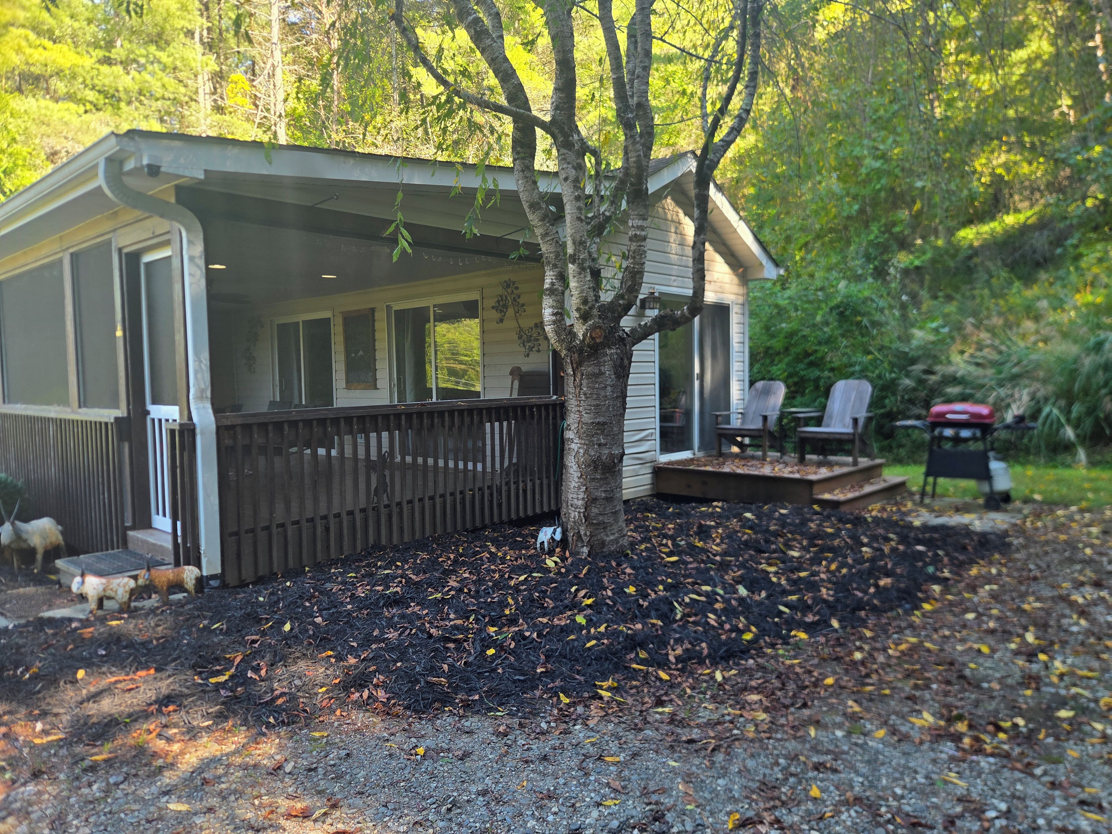 A covered outdoor area with a wooden deck, a barbecue grill, and a seating arrangement.