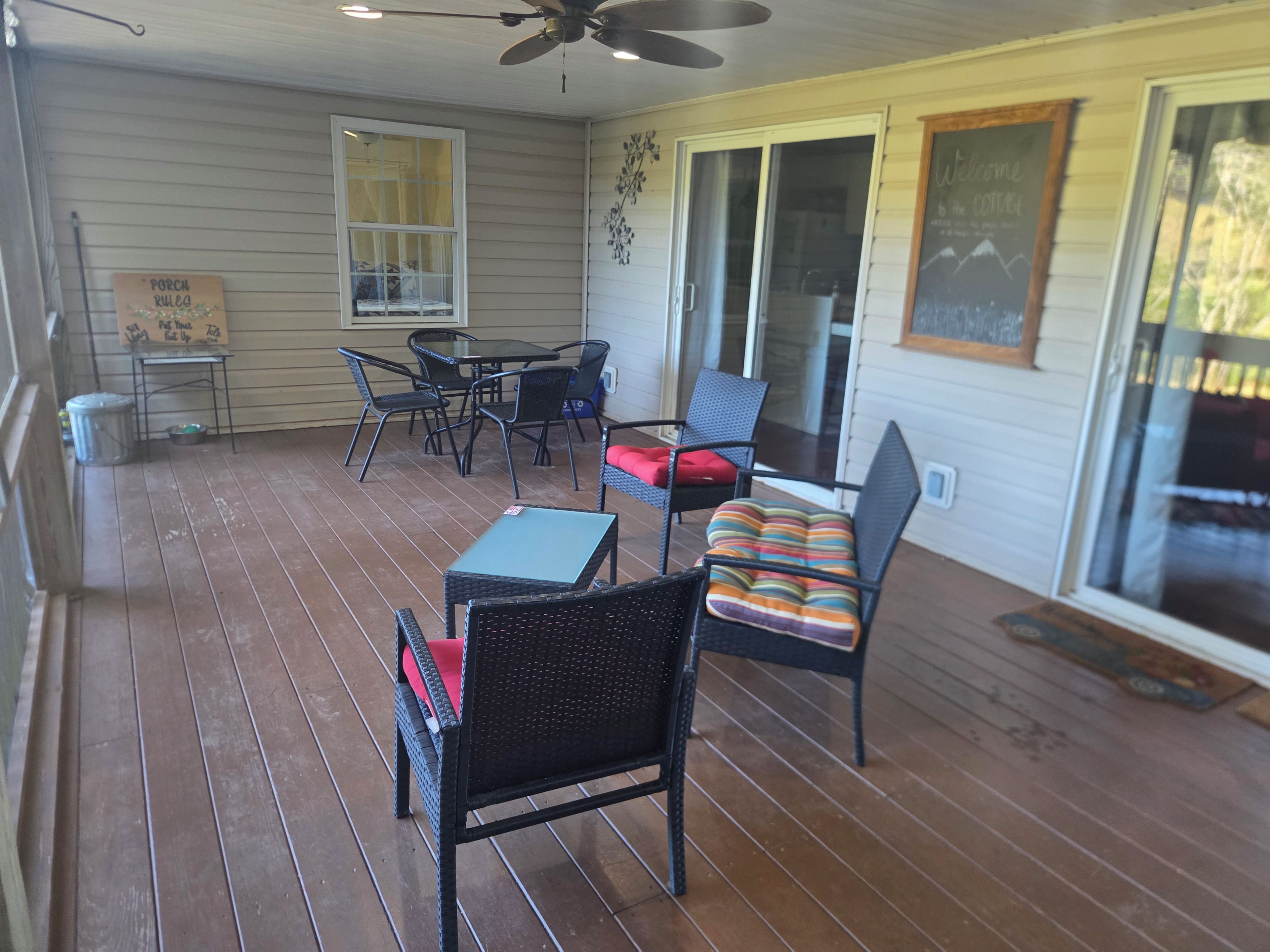 A covered patio area with a ceiling fan, a table with chairs, and a cushioned bench.