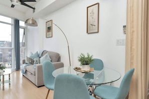 Ein modernes Wohnzimmer mit einer Couch, einem Glastisch und blauen Stühlen.