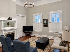 A living room with a fireplace, television, and seating area. - Restored Historic Home with Southern Porch Charm / Walk to Downtown Eufaula (Eufaula)