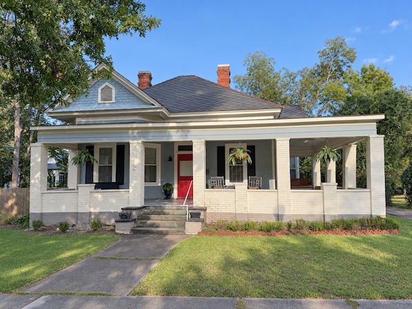 A two-story house with a front porch, a red door, and a chimney. - Restored Historic Home with Southern Porch Charm / Walk to Downtown Eufaula (Eufaula)