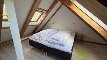 A bedroom with a bed, a bedside table, a lamp, and a skylight.