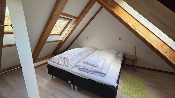 Un dormitorio con cama, mesita de noche, lámpara y tragaluz.