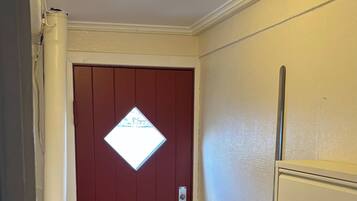 A hallway with a red door, a white radiator, and a tiled floor.