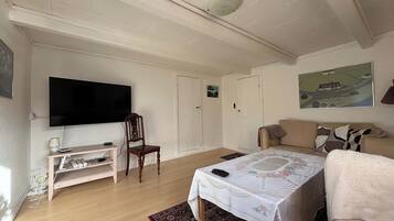 A room with a bed, a television, a chair, a sofa, and a painting on the wall.