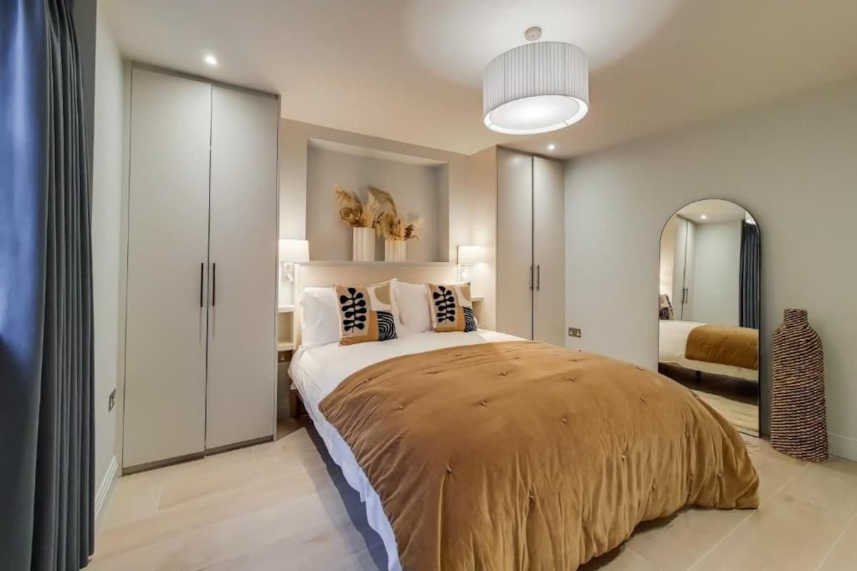 Ein Schlafzimmer mit einem großen Bett, einem Kleiderschrank, einem Spiegel und einer Pendelleuchte.