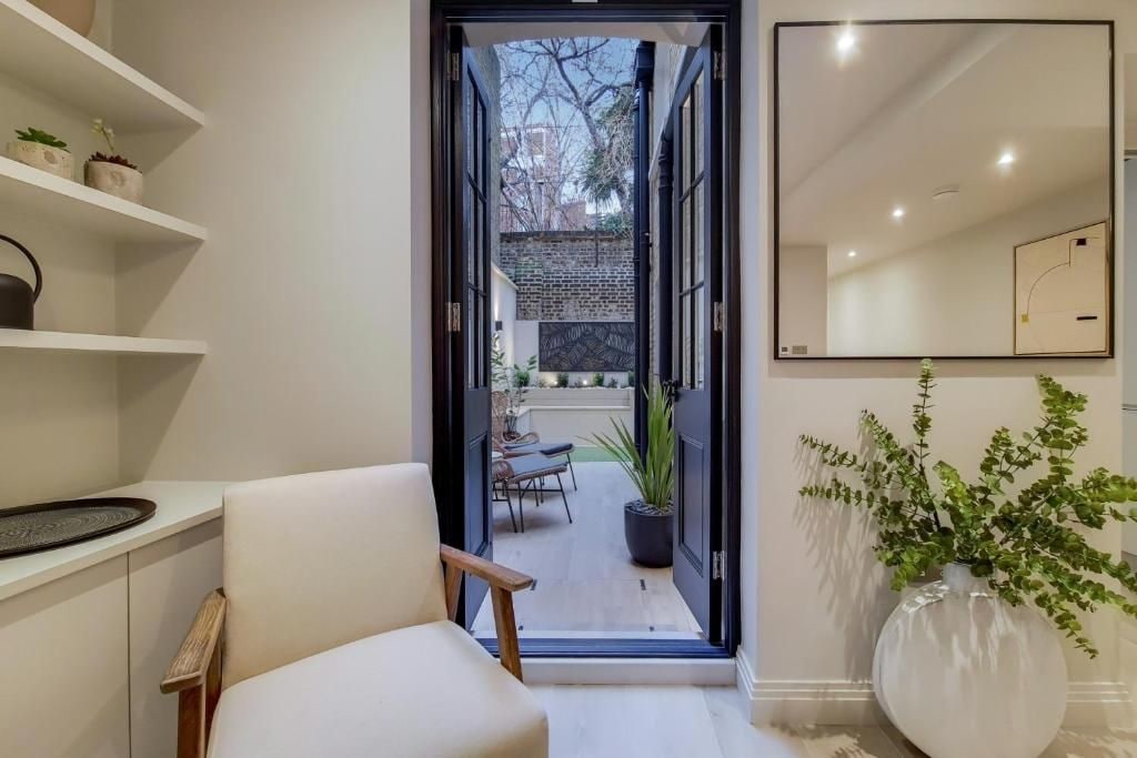 A modern interior with a white chair, a large mirror, and a potted plant.