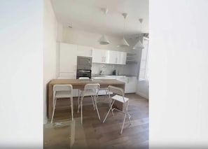 Eine moderne Küche mit weißen Schränken, einer zentralen Kochinsel mit Sitzgelegenheit und Pendelleuchten.