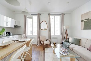 Ein modernes Wohnzimmer mit einem Glastisch, einer Couch und einem Essbereich mit Holztisch und Stühlen.
