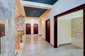 A hotel hallway with marble flooring, a plant, and a digital display. - Classic Hotel Dream Palace (Danapur)