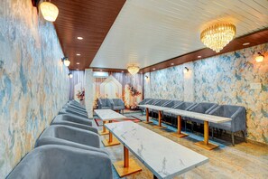 A hotel room with a long dining table, multiple seating options, and a chandelier. - Classic Hotel Dream Palace (Danapur)