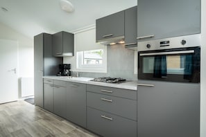A modern kitchen with grey cabinetry, a built-in oven, and a gas stove.