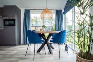 A modern kitchen with a built-in oven and a dining area with a wooden table and blue chairs.
