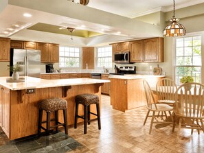 A spacious kitchen with wooden cabinets, a large island with stools, and a dining area with wooden chairs. - Take in sweeping panoramic views from this 3-bed, 3-bath penthouse in the heart of Sebastian. (Sebastian)