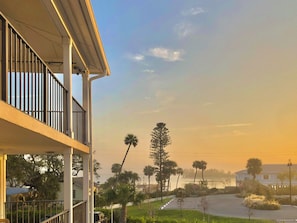 A residential balcony with a view of a street lined with palm trees and a distant building. - Take in sweeping panoramic views from this 3-bed, 3-bath penthouse in the heart of Sebastian. (Sebastian)